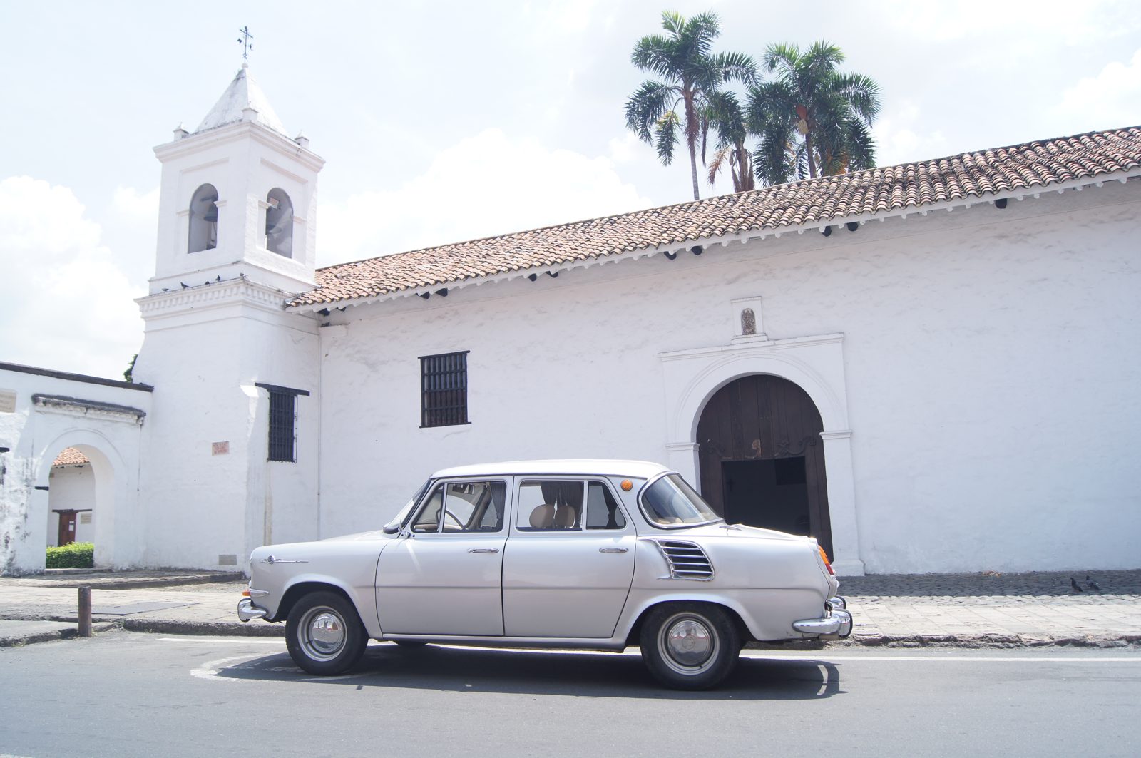 Škoda 1200 plateado — perfil lateral frente a iglesia colonial